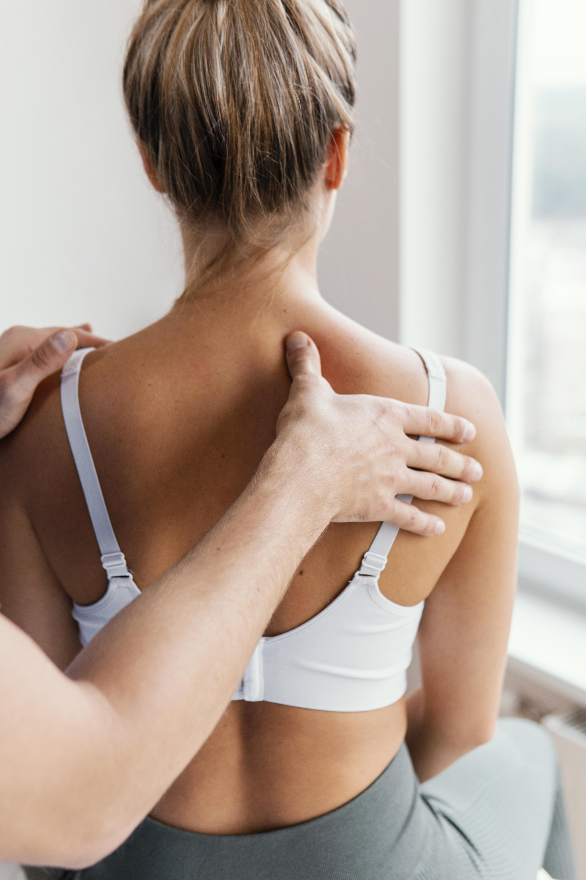 Male osteopathic therapist checking female patient s upper spine